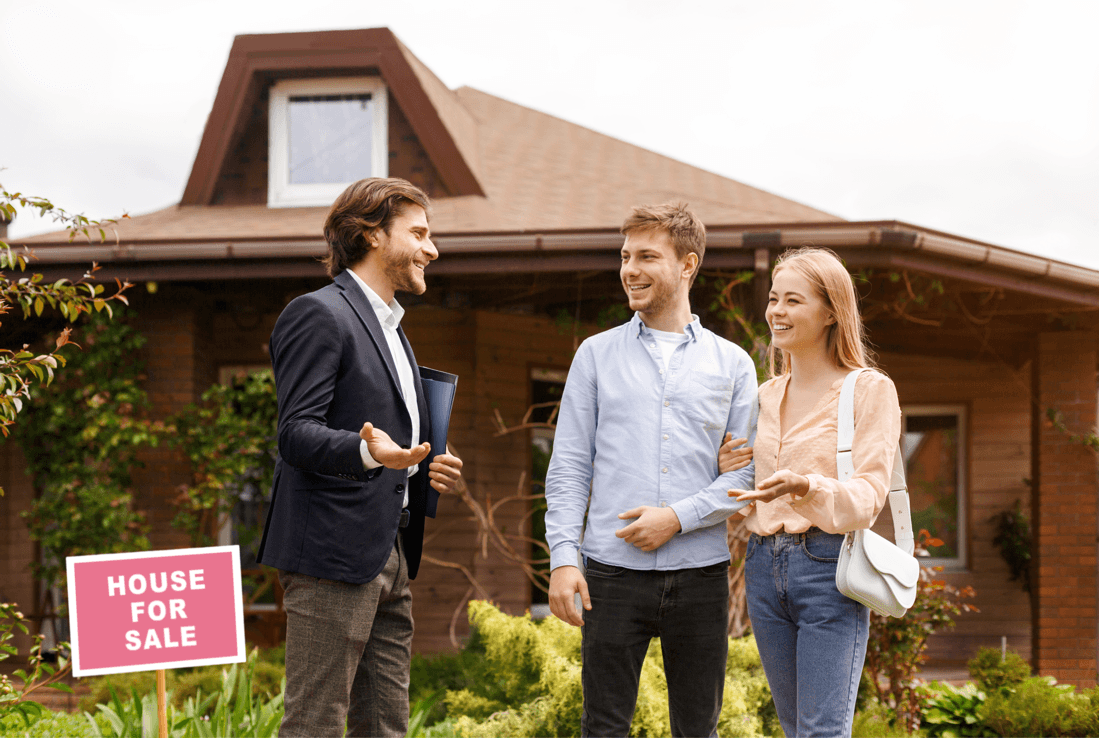 An image of a young couple being shown a house for sale by a realtor.